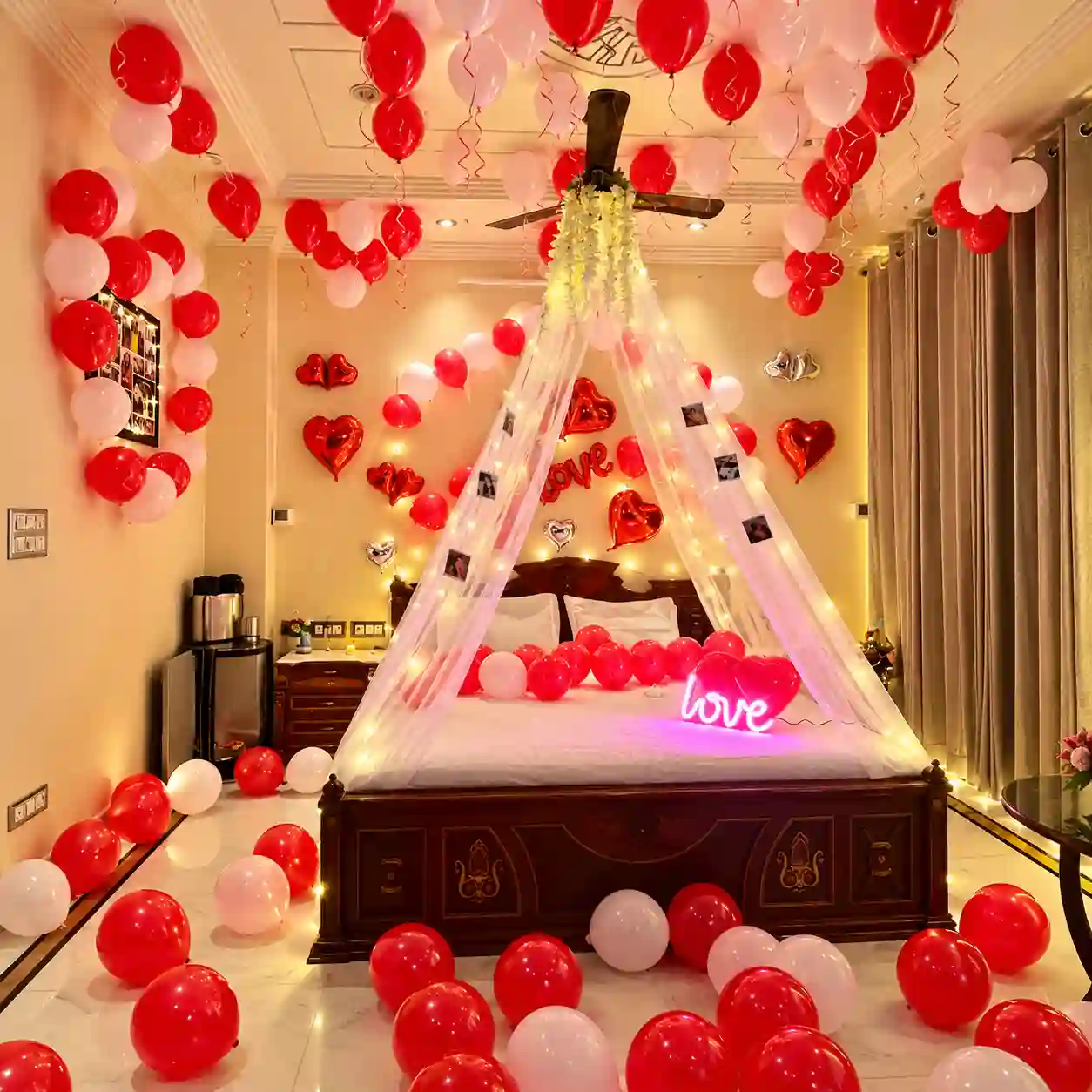 Romantic red and light pink love canopy bedroom decoration with 150 balloons, net canopy, fairy lights, hanging photographs, heart foil balloons and LED LOVE sign.