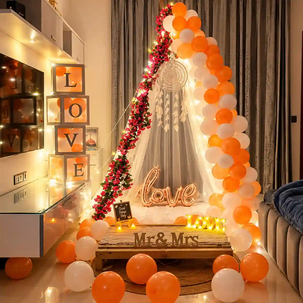 Romantic orange and white balloon canopy decoration with red flowers, fairy lights and LOVE letters